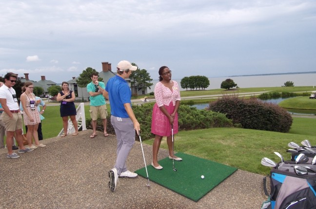 Lady Taking Swing with Instructor Giving Advice and Spectators Watching
